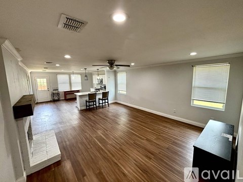 A living room with a wooden floor and a dining area with a table and chairs.