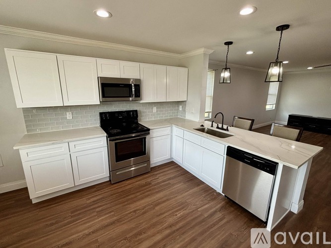 A modern kitchen with white cabinets and stainless steel appliances.