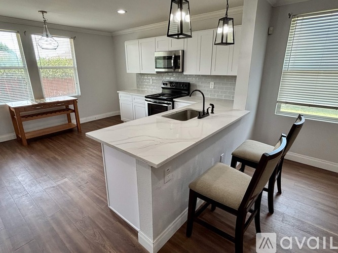 A kitchen with a white island and wooden chairs.