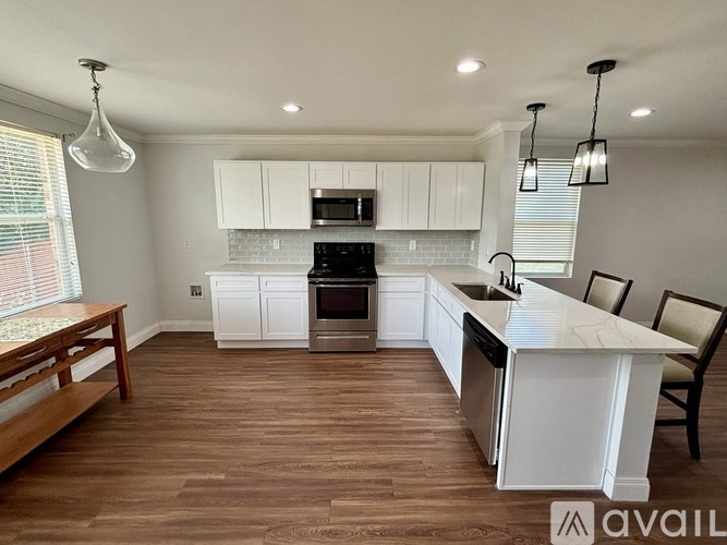 A modern kitchen with white cabinets and a wooden floor.