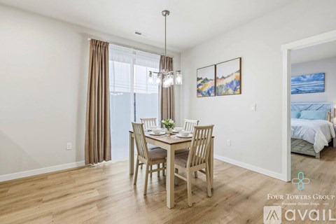 A dining room with a wooden table and chairs, a chandelier, and a painting on the wall.