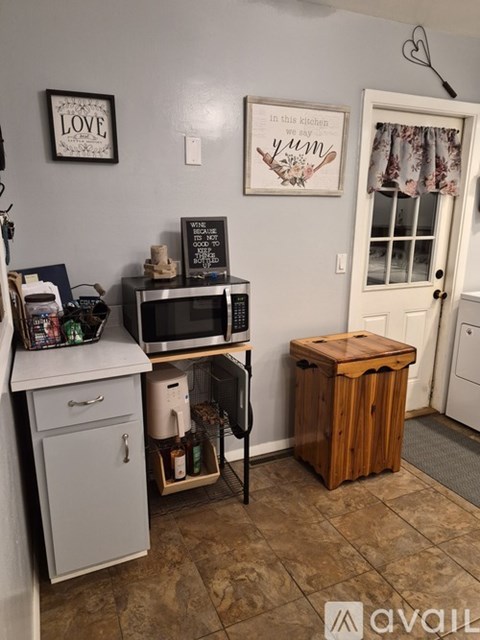 A kitchen with a white cabinet and a microwave on top of it.