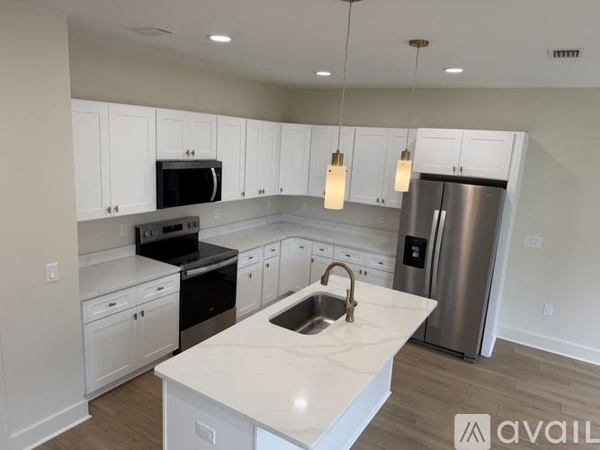 A kitchen with white cabinets and a marble countertop.