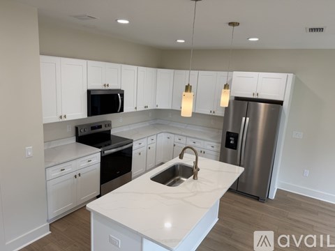 A kitchen with white cabinets and a marble countertop.