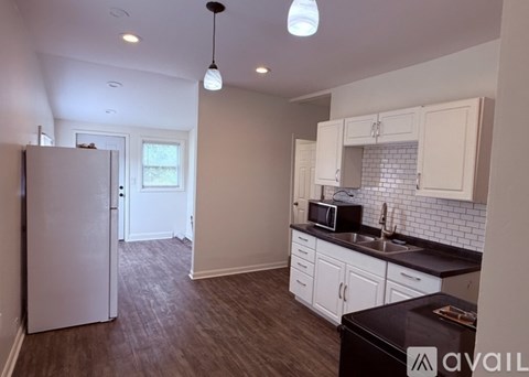 A kitchen with white cabinets and a black countertop.
