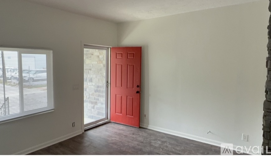 A room with a red door and a window with blinds.