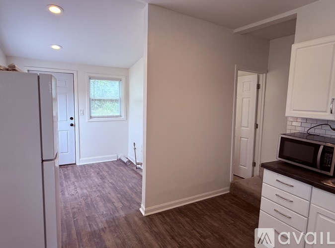 A kitchen with a refrigerator, microwave, and cabinets.