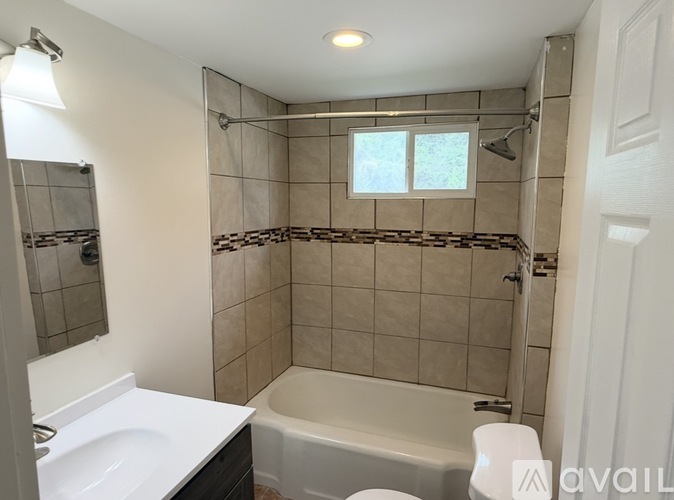A bathroom with a white tub, sink, and tiled walls.