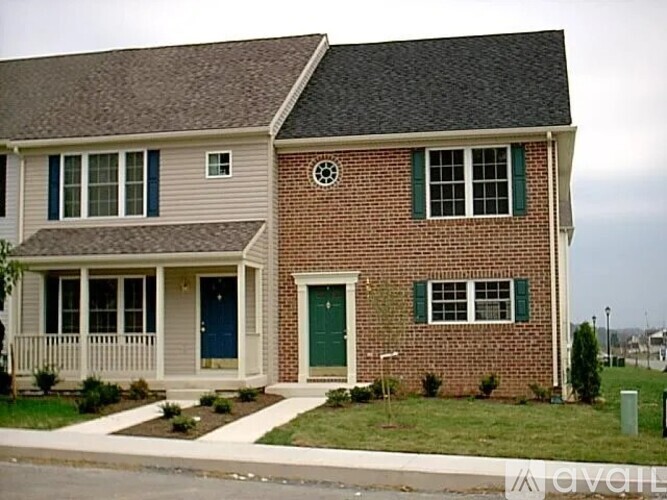 A brick house with a blue door and green shutters.