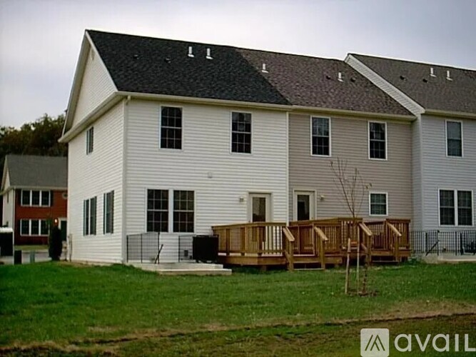 A two-story house with a white exterior and a brown deck.