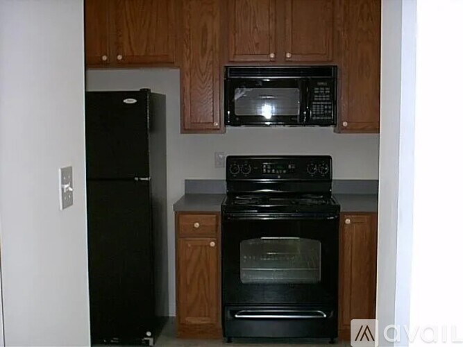 A black oven and microwave in a kitchen with wooden cabinets.