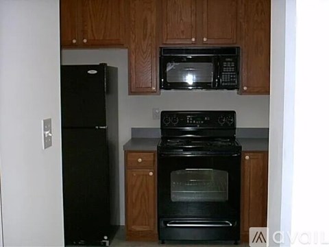 A black oven and microwave in a kitchen with wooden cabinets.