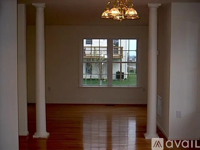 A room with a chandelier, a window, and a wooden floor.