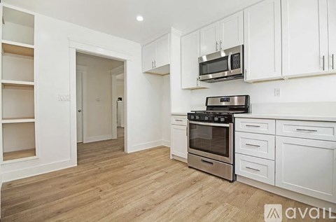A kitchen with white cabinets and a wooden floor.
