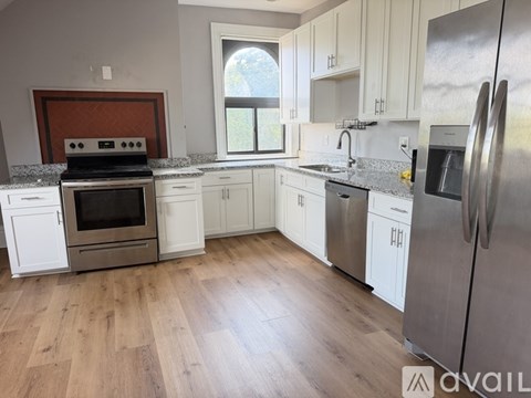A kitchen with white cabinets and a wooden floor.
