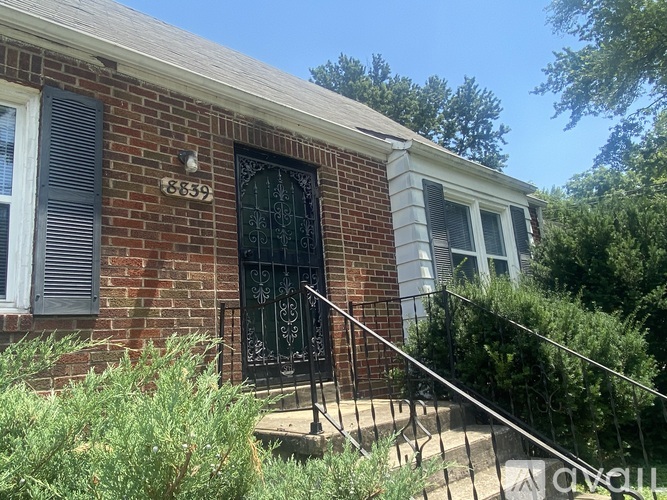 A red brick house with a black door and a number 6839 on the wall.