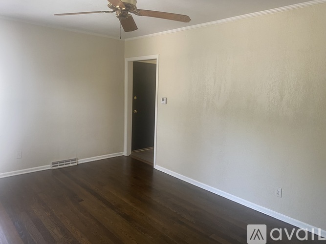A room with a ceiling fan and wooden flooring.