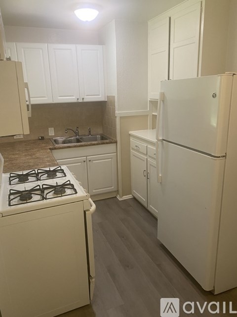 A kitchen with a white stove and white cabinets.