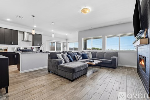 A modern living room with a grey couch and a fireplace.