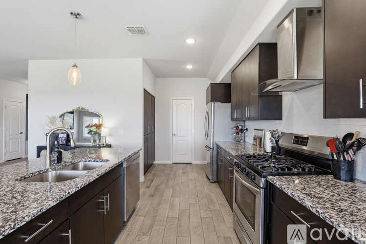 A kitchen with dark brown cabinets and a granite countertop.