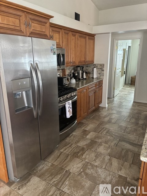A kitchen with a stainless steel refrigerator and wooden cabinets.