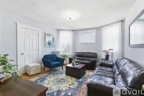 A living room with a black leather sofa and a blue armchair.