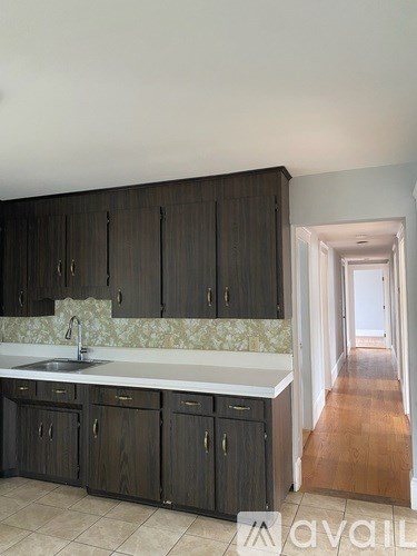 A kitchen with dark wood cabinets and a marble backsplash.