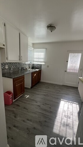 A kitchen with wooden floors and white cabinets.