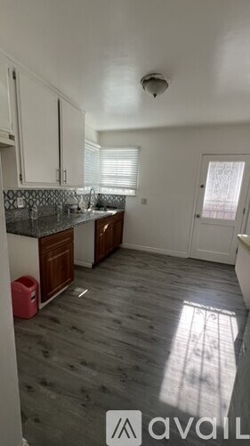 A kitchen with wooden floors and white cabinets.