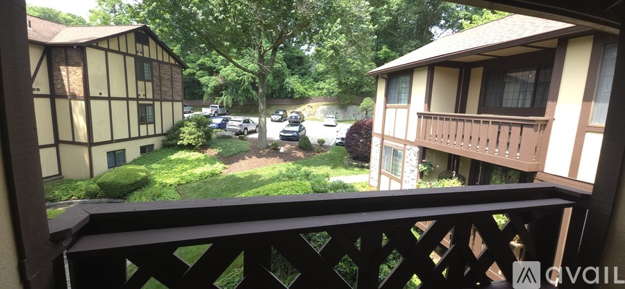 A balcony view of a building with a black railing and a tree in the background.