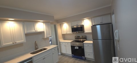 A kitchen with a refrigerator, stove, and cabinets.