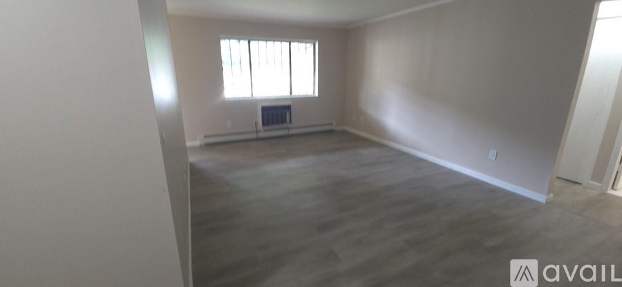 A spacious room with wooden flooring and a window.