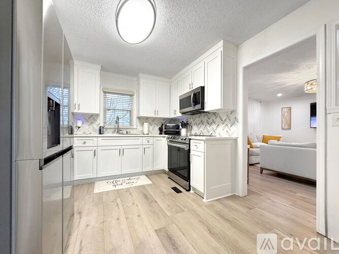 A kitchen with white cabinets and a wooden floor.