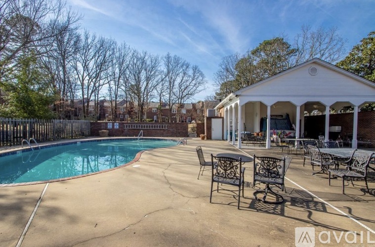 A pool area with a white pavilion and black metal chairs.
