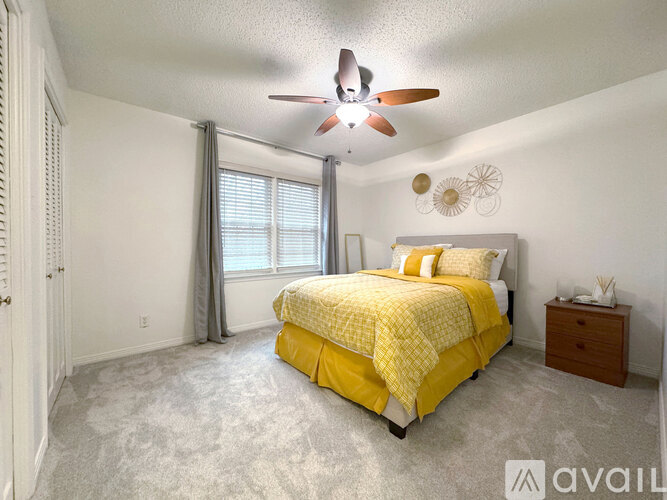 A bedroom with a yellow bed and a ceiling fan.