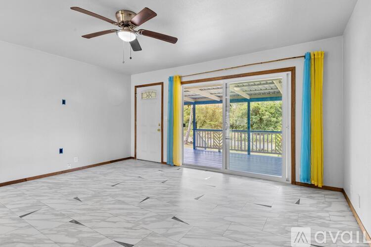 A room with a ceiling fan and sliding glass doors.