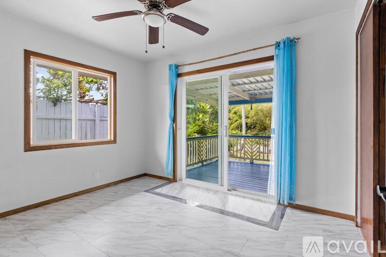 A room with a ceiling fan and sliding glass doors leading to a balcony.