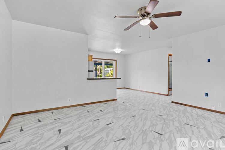 A room with a ceiling fan and a window with a view of trees.