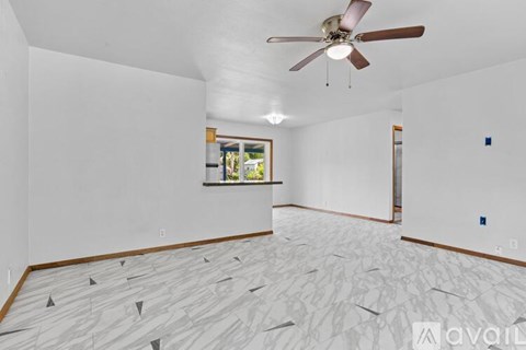 A room with a ceiling fan and a window with a view of trees.
