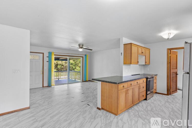 A kitchen with wooden cabinets and a black countertop is available for rent.