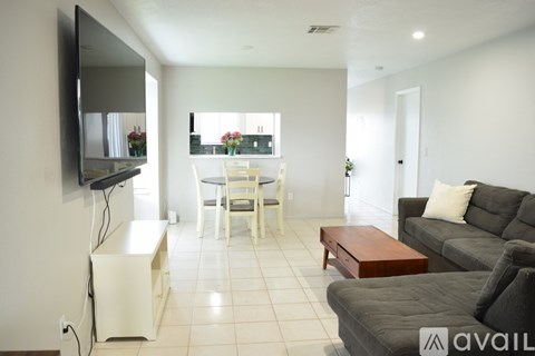 A living room with a television, a dining table, and a couch.