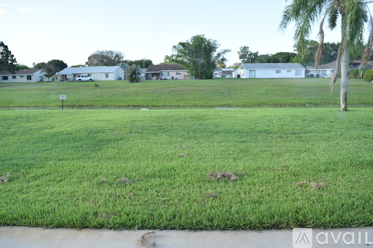 A grassy field with a few buildings in the background.