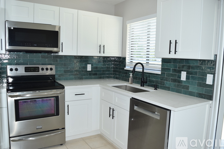 A kitchen with white cabinets and a stove top oven.