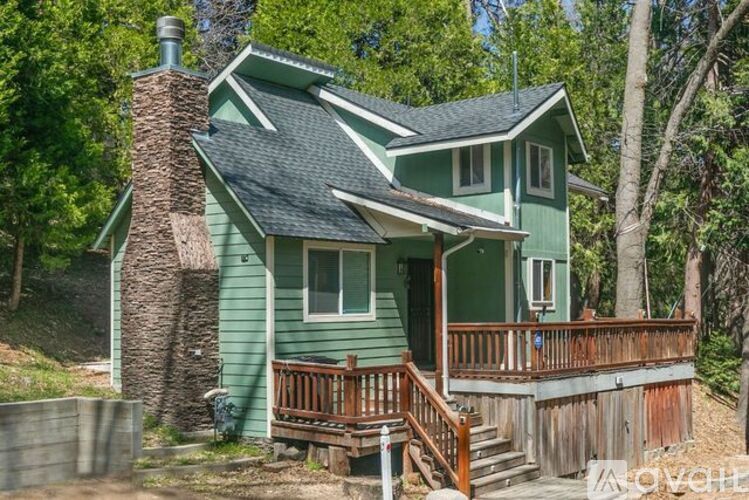 A green house with a wood deck and a chimney.