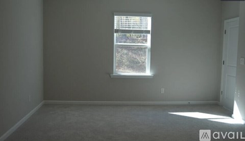 A room with a window and a carpeted floor.