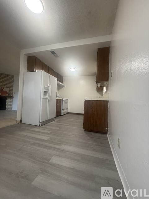A kitchen area with a white refrigerator and wooden cabinetry.