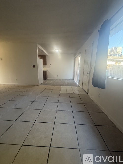 A spacious room with tiled flooring and a doorway leading to another room.