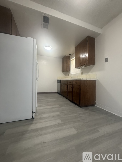 A kitchen with a white refrigerator and wooden cabinets.