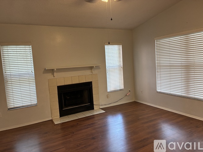 A living room with a fireplace and two windows.