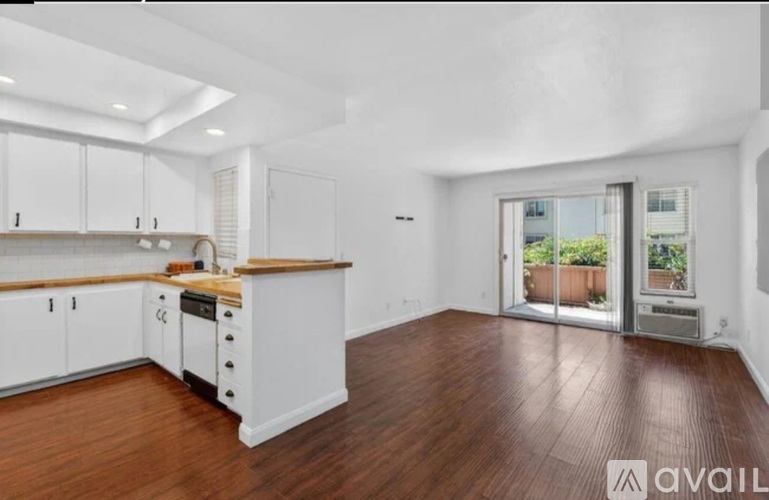 A spacious kitchen with white cabinets and a wooden countertop.